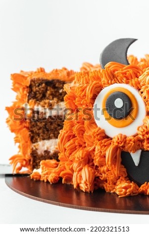 Monster theme cake on the white background. Halloween cake with orange fluffy cream cheese frosting isolated on white