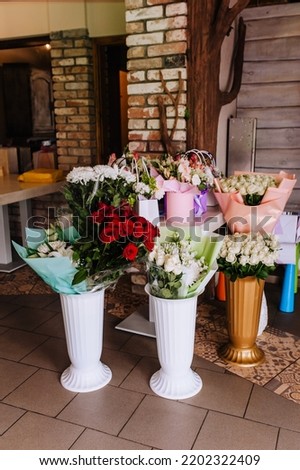 Many white vases with multi-colored flowers in the package, paper baskets are in the interior of the restaurant. Photography, holiday.