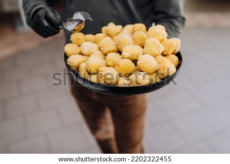 The male waiter holds a plate in his hands, a tray with fried cheese, meat in yellow batter. Food photography.