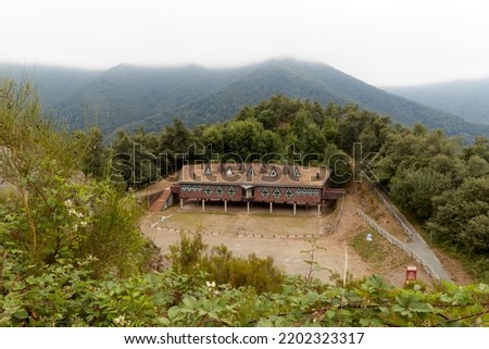 Foggy landscape with a house built in a clearing in the mountains. Horizontal photography.