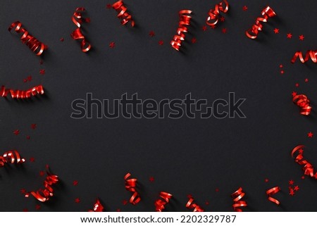 Frame of red party streamers and confetti on black background. Black Friday sale banner design. Flat lay, top view, copy space.