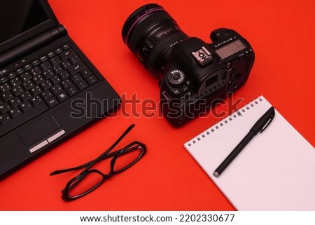 Top view of photojournalist concept with photo camera, notepad and laptop. Office tools. Royalty-Free Stock Photo #2202330677