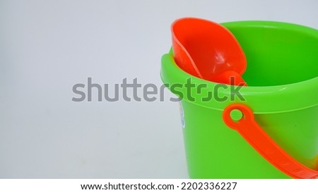 Kids green bucket and red spade summer holiday concept isolated against white background
