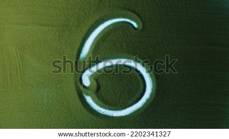 Hand drawing Number Six 6 Symbol in the Green Sand. Male hand writes a number on the green sand with backlight. It is a series from 0 to 10. Top view 4k resolution