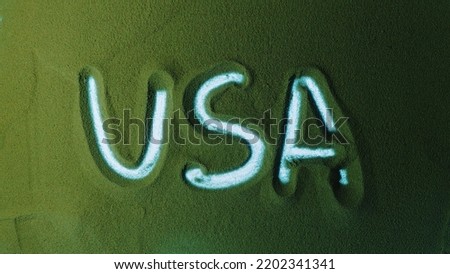 Hand drawing the USA in the Green Sand. Male hand writes the word USA on the green sand with white backlight. Top view 4k resolution