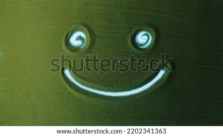 Hand drawing the Smile symbol in the Green Sand. Male hand writes peace symbol on the green sand with white backlight. Top view 4k resolution