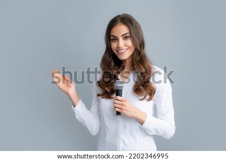 Woman speech, business woman holding a microphone. Public speaking with microphone, speaker speech presentation concept. Beautiful stylish woman singing karaoke isolated over gray background.