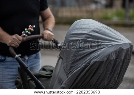 Walking in the rain with a pram with a waterproof raincoat covered in drops Royalty-Free Stock Photo #2202353693