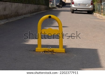 yellow metal fencing prohibiting entry to the parking space. yellow parking barrier on concrete. Mechanical barrier prohibiting the use of a parking space.