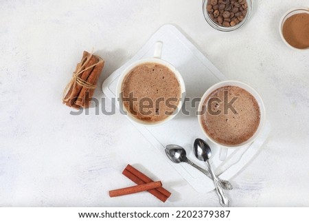 Coffee drink with milk and whipped cream, cappuccino coffee, latte, cinnamon, coffee beans on a gray concrete table, modern coffee shop advertisement, selective focus, top view, space for text,