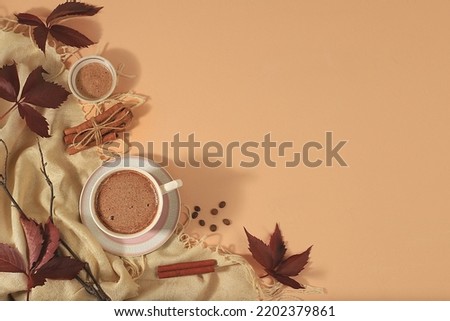 Cozy home table with cappuccino coffee,coffee beans cinnamon,autumn leaves,healthy breakfast with ingredients, hello autumn concept, hygge style, modern coffee shop advertisement, selective focus,