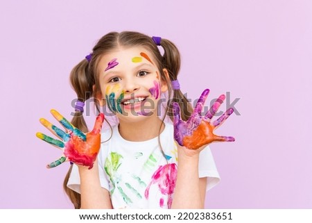 A child stained in multicolored paints will have to be creative. The concept of children's creativity on a pink isolated background. Royalty-Free Stock Photo #2202383651