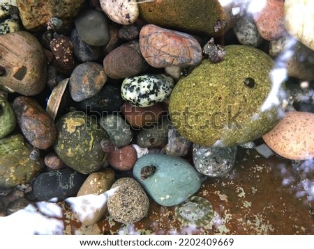 Photo of colourful rocks in the Atlantic Ocean. There is some reflections in the water.