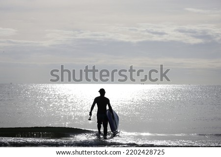 A man catching surf board and walking to the sea alone