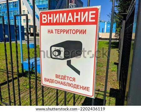 Close-up of a sign on an iron fence. Translation: Attention, the territory is under video surveillance.