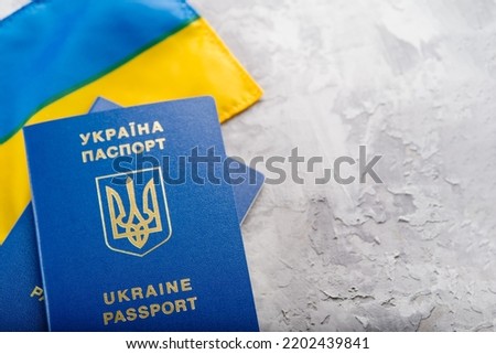 Yellow-blue flag of Ukraine and two biometric Ukrainian passports on a gray background. Travel abroad, emigration. There are no people in the photo. There is free space to insert.