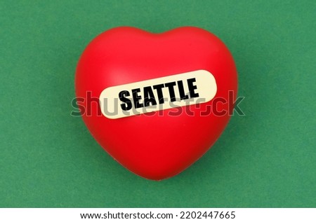 Love for the city, homeland. On a green surface lies a red heart with the inscription - Seattle