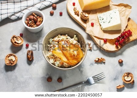 Pear and gorgonzola oatmeal with walnuts on concrete table.