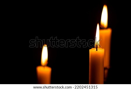 Three burning candles in the dark. Candle flame in darkness. Candles flames in dark. Three candles burning Royalty-Free Stock Photo #2202451315