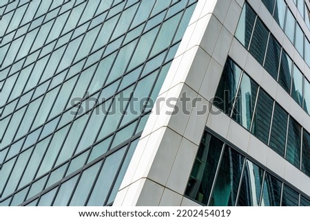 Fragment of a modern office building. Abstract geometric background. Part of the facade of a skyscraper with glass windows.