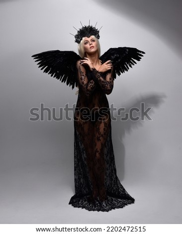 portrait of beautiful  model  wearing black gothic dress with headdress  and feathered angel wings.  isolated on studio background.