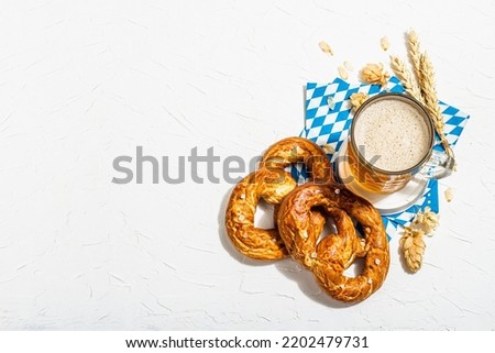 Traditional Oktoberfest set. Pretzels, beer, traditional pattern napkin. German festival food concept. Trendy hard light, dark shadow, white putty background, top view Royalty-Free Stock Photo #2202479731
