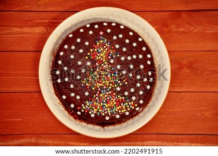Cake. chocolate cake decorated with a Christmas tree and white snowflakes. on a white plate. a cake on a wooden background. The concept of Christmas and New Year. view from above.close-up.