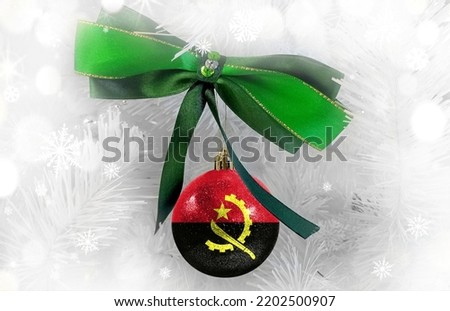 New Year's glass ball with the flag of Angola against a colorful Christmas background