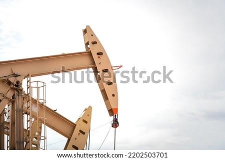 Oil beam pump or Donkey pump which is use to increase crude oil production from downhole, photo taken with blue sky background. Oil and gas industry or business photo.