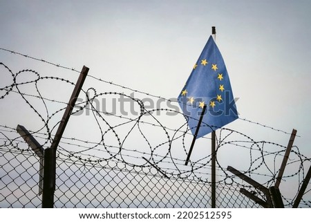 View of European union flag behind barbed wire against cloudy sky. Concept anti-Russian sanctions. border post on border of Russia. cancel culture Russia in world. ban on entry for Russians to Europe