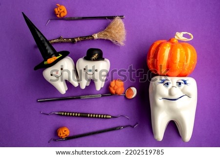 
dental concept. figurines of teeth in halloween costumes and dental instruments. pumpkins and a broom.on a purple background