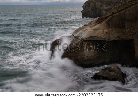 Waves splashing onto rocks at Tunnel Beach, Dunedin. Picture taken using slow shutter speed showing motion of the waves. 