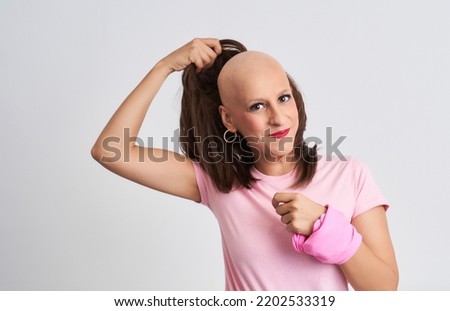 Woman with cancer taking off her wig showing her hairless head Royalty-Free Stock Photo #2202533319