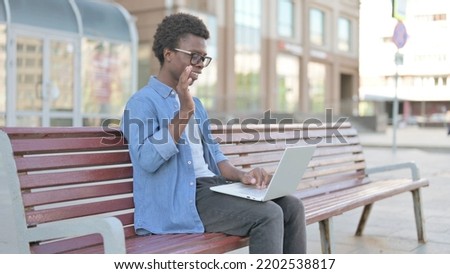 Young African Man Talking on Video Call while Sitting Outdoor on Bench