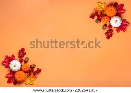 Autumn bouquet of acorns, berries, maple leaves, pumpkins isolated on orange background Flat lay Top view Floral border Holiday card Hello September, October, November concept.