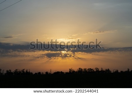orange sunset on a background of clear blue sky clouds and trees shot in the evening in the village in summer