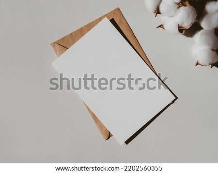 Blank white card, envelope and branch part on light grey background top view. Design element for wedding invitation, thank you card, greeting, business card