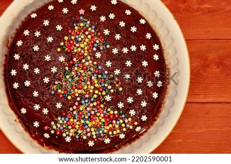 Cake. chocolate cake decorated with a Christmas tree and white snowflakes. on a white plate. a cake on a wooden background. The concept of Christmas and New Year. view from above.close-up