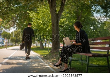 An attractive businesswoman is looking at the businessman who suddendly passed in front of her while she was working on her lap top