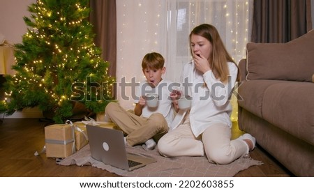 Brother and sister watch Christmas movies on a laptop
