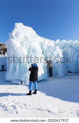 Baikal Lake on sunny winter day. Favorite pastime of tourists is photographing unusual icy rocks of Olkhon Island, covered with bizarre icicles. Unforgettable ice travel, winter outdoor recreation