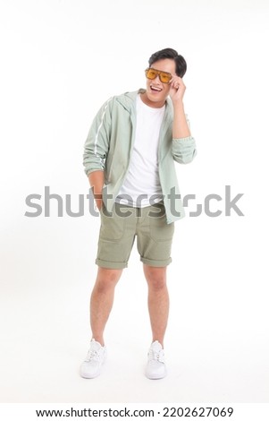 Full body length photo of a young handsome Asian adult man, in summer casual wear, with hand gesture, isolated on white background. Concept of travel or tourist promotion
