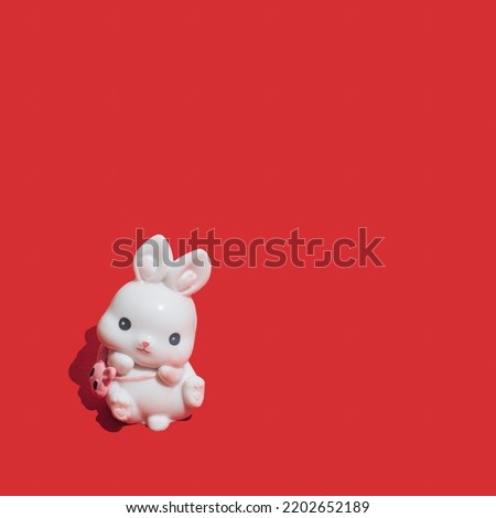 Little white rabbit on vibrant red background. Symbol of the Chinese New Year of the rabbit. Happy 2023 and good luck!