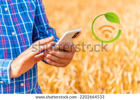 Man farmer using phone in a wheat field.Agriculture technologies,infographics.Closeup.Selective focus.