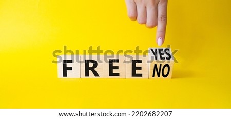 Free symbol. Businessman points at wooden cubes with words Free YES to Free No. Beautiful yellow background. Business concept. Copy space