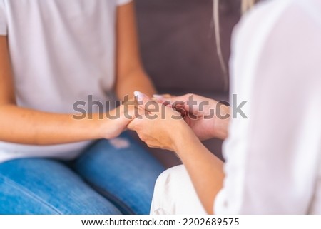 mom or psychologist, talks to the child holding hands, supporting at home, expressing emotions. an anxious teenage girl listens to a psychologist at a meeting talking about her problems. Close-up Royalty-Free Stock Photo #2202689575