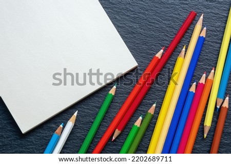 Colorful colored pencils and open sketchbook. Flat lay, free space for text or picture