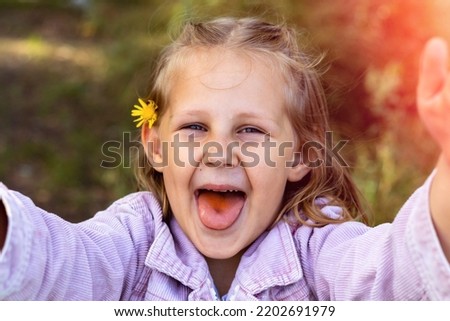 Smiling little girl in the park. Copy space. Happy child looking at the camera. Portrait of a laughing kid outside.