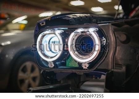 Installing the headlight on the car. Repair of car headlights. Tuning and restoration of automotive optics. Installation of the Bi LED lens in the headlight housing. Royalty-Free Stock Photo #2202697255