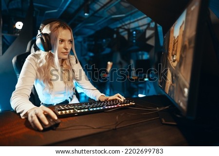 Blonde cyber gamer playing a computer game. Cyber club with neon light. High quality photo